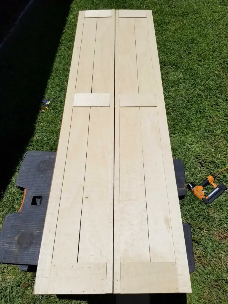 wood bifold barn door laid out and in process on a table in the green grass