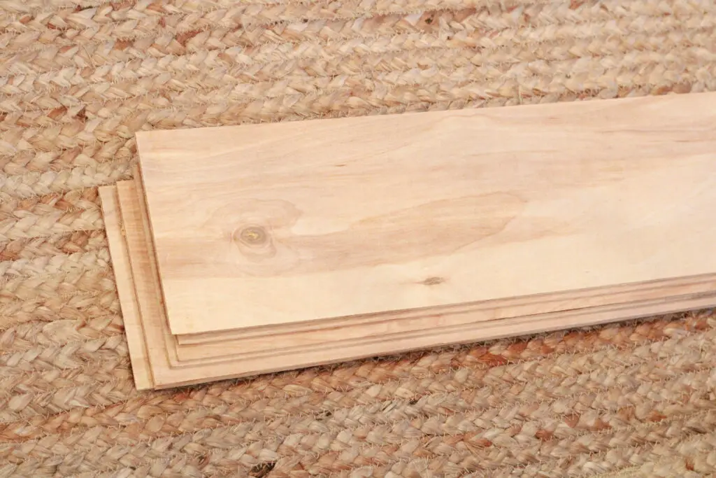 a stack of cut thin underlayment boards that were cut into strips on top of a jute rug on the floor 