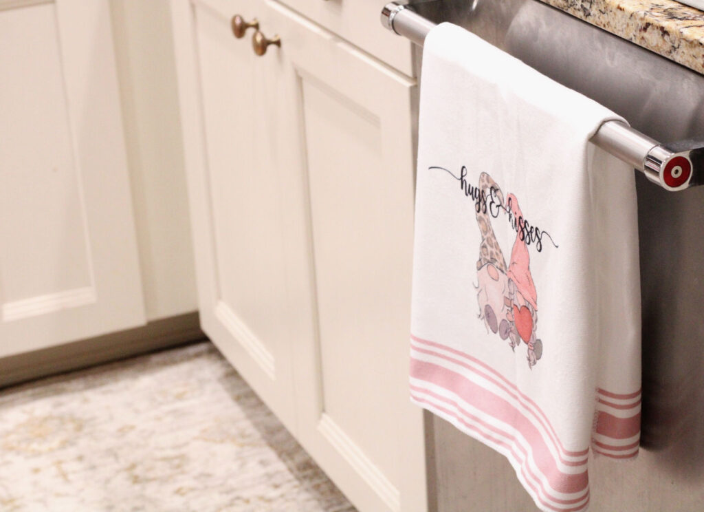 valentines day red and pink gnome kitchen towel hanging on a dishwasher