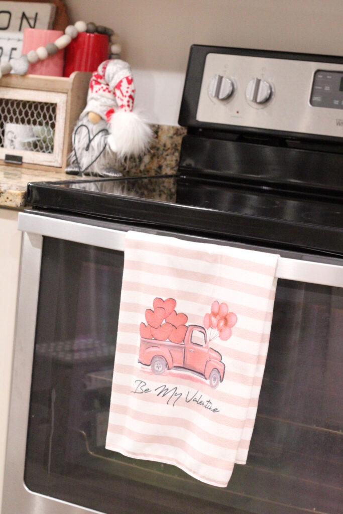 valentines day red truck with pink hearts on a kitchen towel hanging on an oven