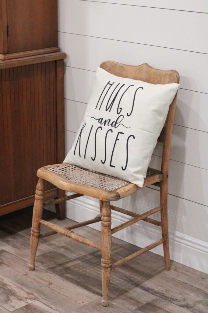 wood antique chair with valentines day pillow that says hugs and kisses against a shiplap wall