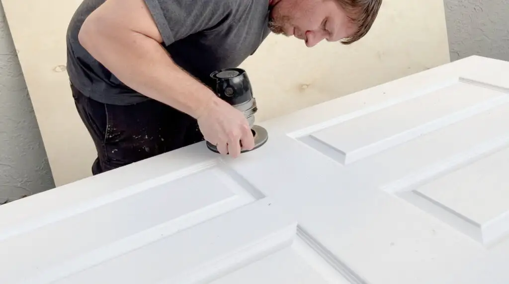 man holding a router and cutting out a door knob hole for a door
