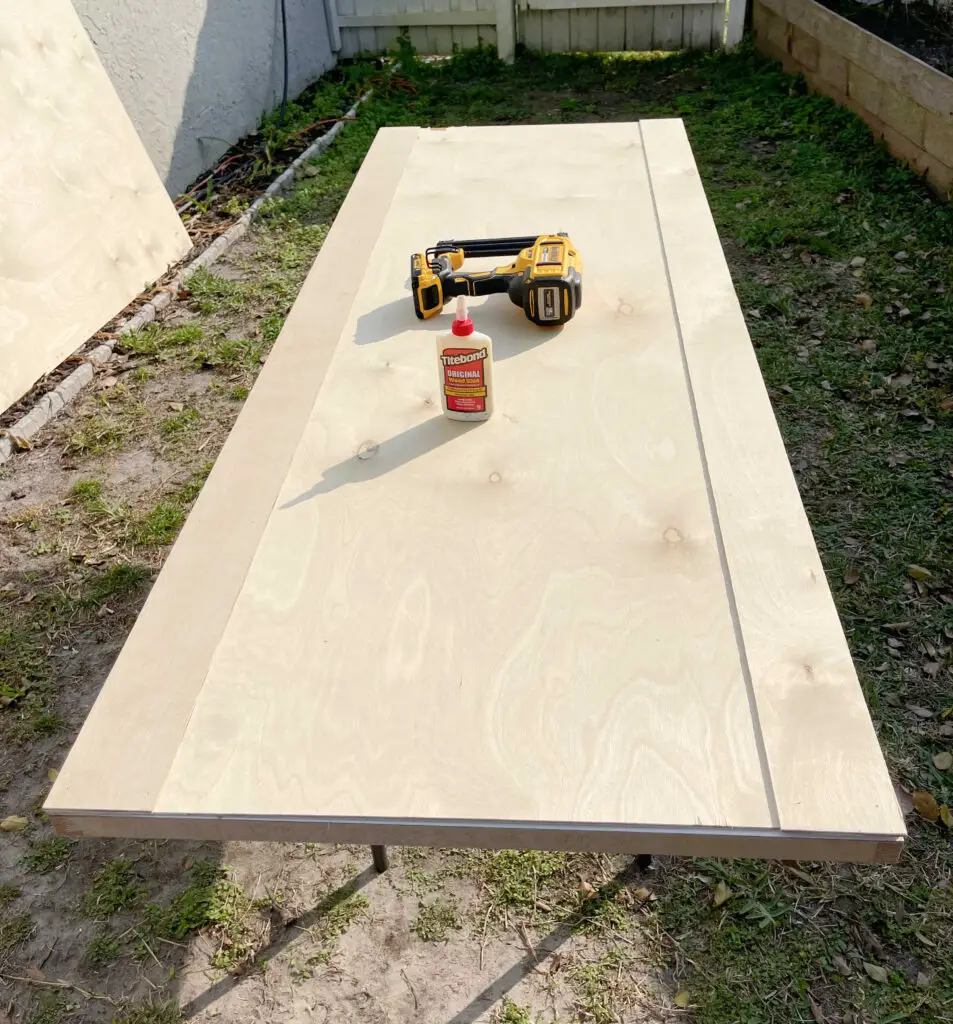 diy farmhouse door with side pieces on and wood glue and nail gun, on a table outside