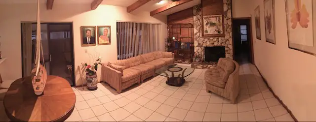 A dining room with dark wood paneling, rock fireplace and white tile floors