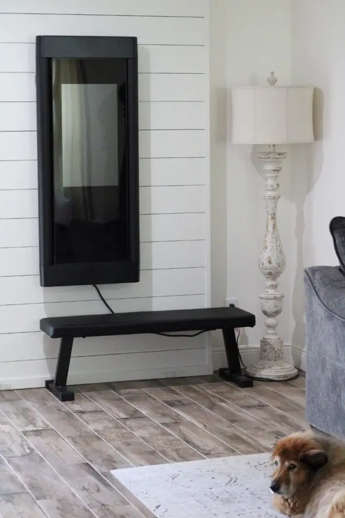 the tonal workout machine hanging on a white shiplap wall in a farmhouse family room