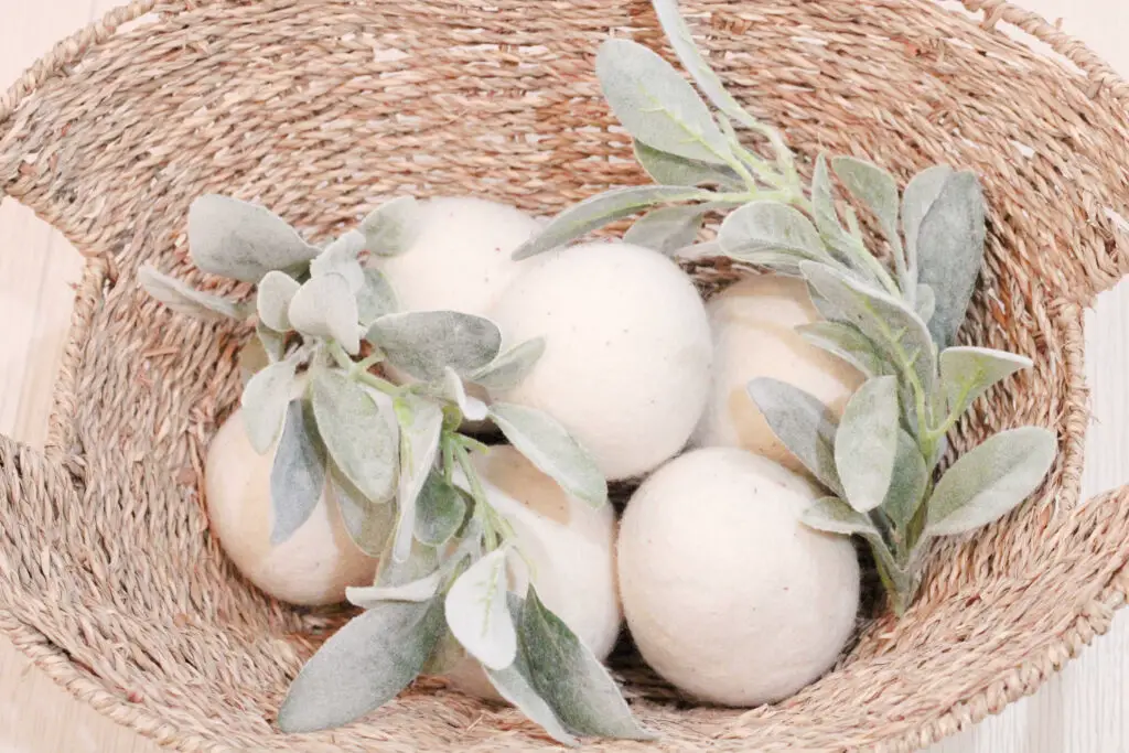 a basket with white wool balls in it and greenery