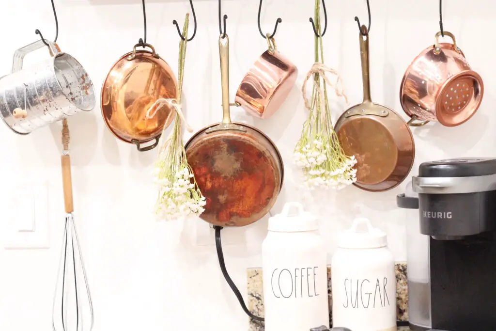 copper pots and pants hanging in a farmhouse kitchen with white florals hanging upside down for spring décor