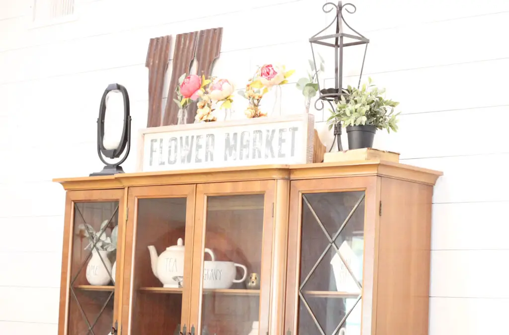 Wood hutch with a Flower Market sign on top and pink peonies and greenery for spring