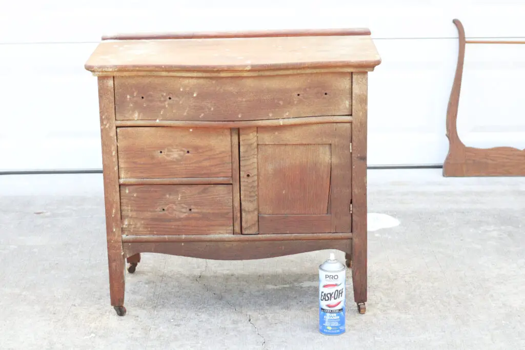 wood colored washstand with oven cleaner white spray on it and a can of oven cleaner next to it on the ground