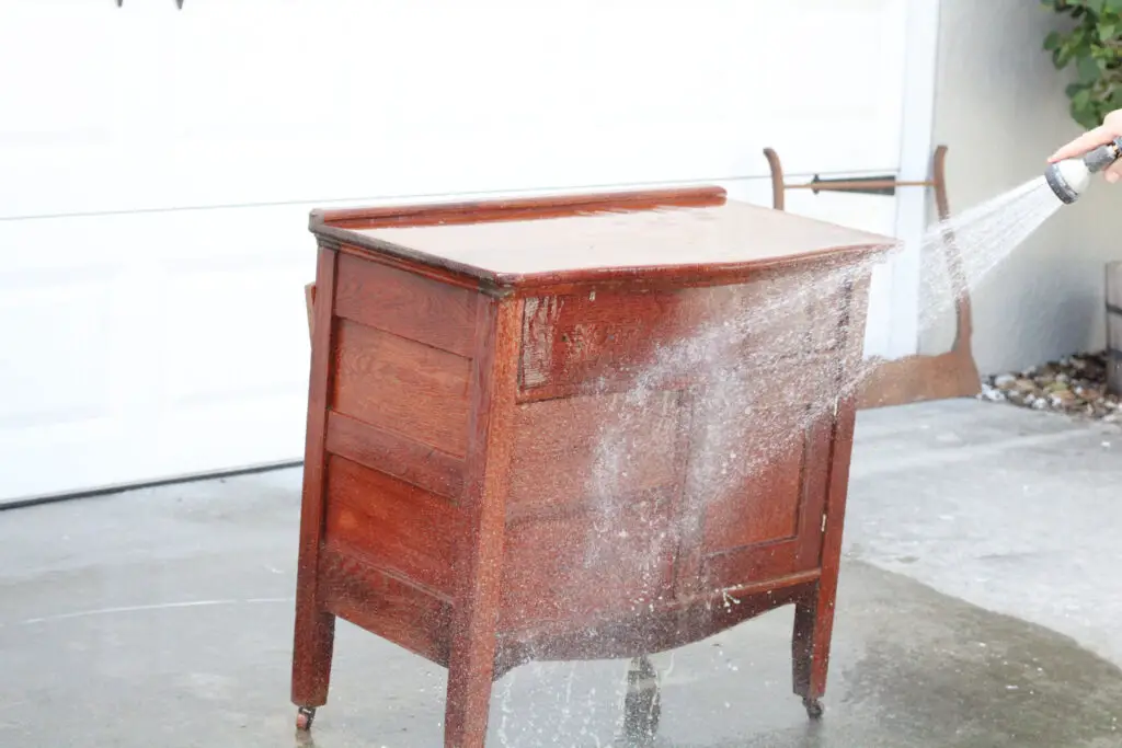 A wood washstand being spray with a water hose