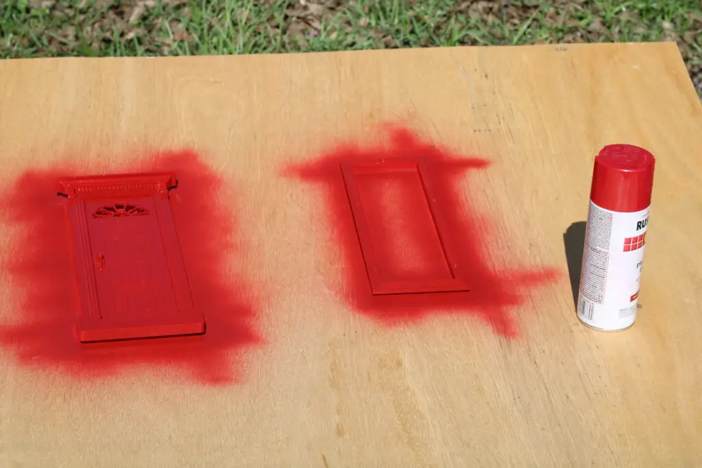 close up of a small door with red spray paint on it and a can of red spray paint on wood. 