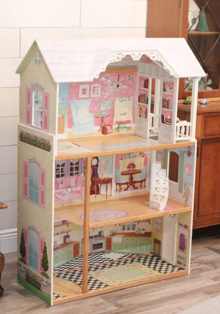close up picture of a wood dollhouse with nothing inside. It is pink, white, and blue wood colors. 