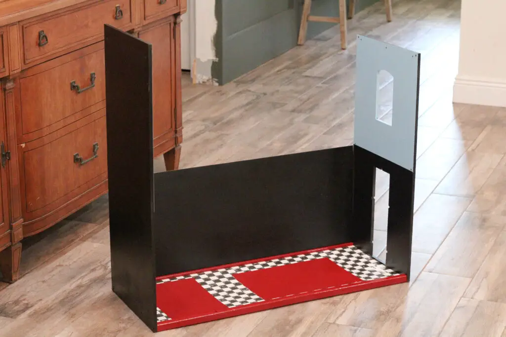 close up of a wood dollhouse that is partially assembled in black and white and red and blue. 