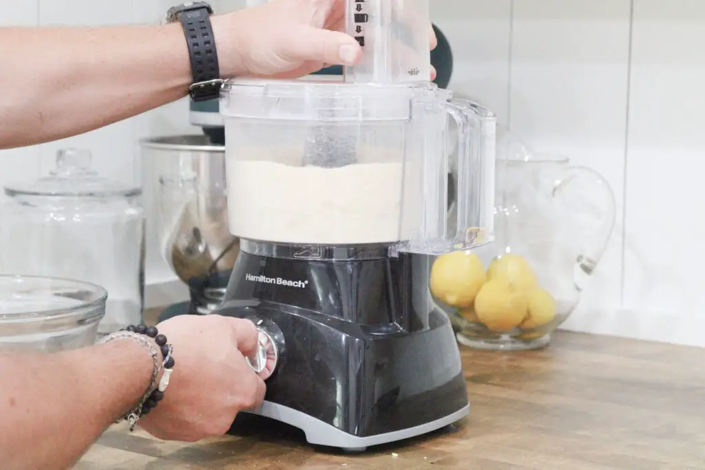 Close up of a man's hands operating a food processor with white soap inside